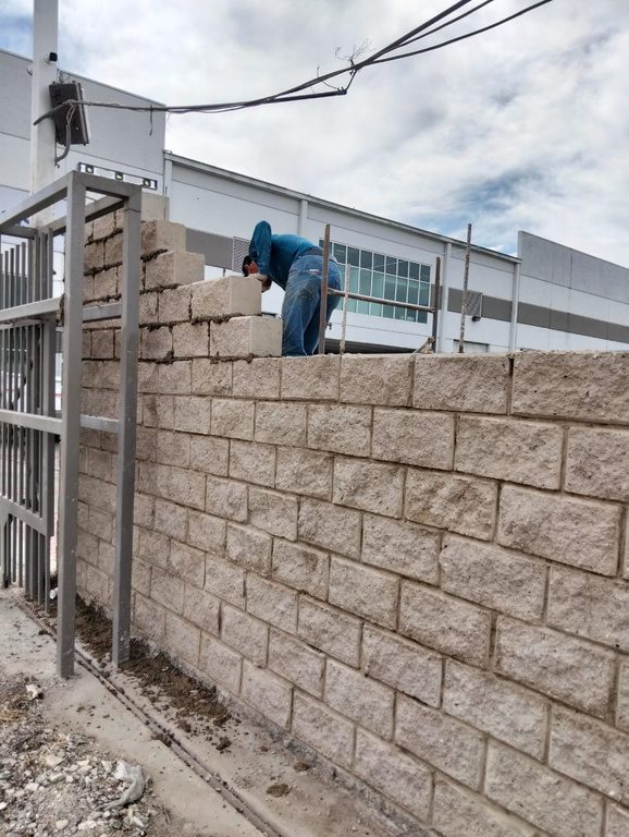 Albañil levantando muro de block sobre estructura metálica