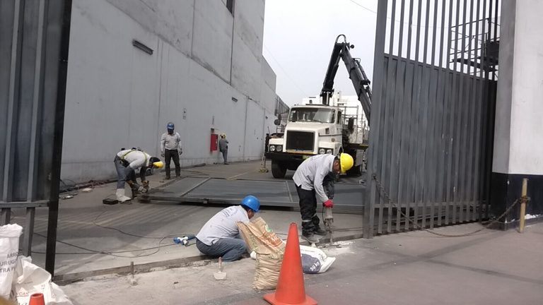 Cuadrilla trabajando en portón industrial con apoyo de grúa