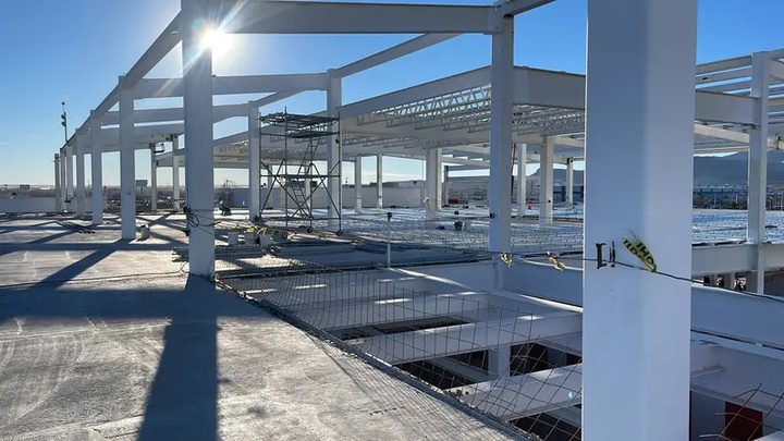 Estructura metálica de nave industrial en proceso de refuerzo bajo cielo despejado