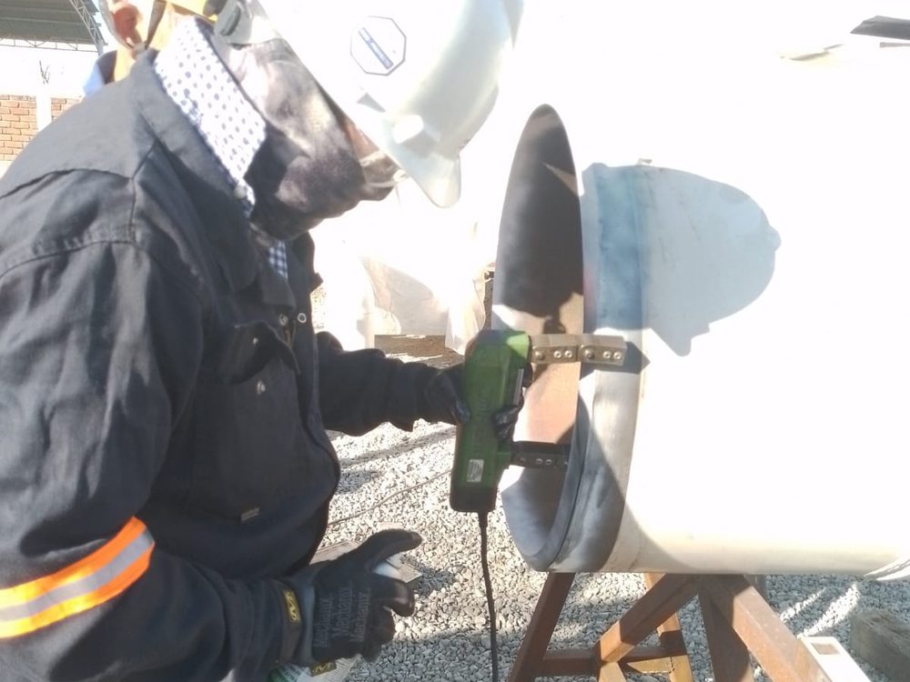 Operador con respirador preparando la superficie de una tubería